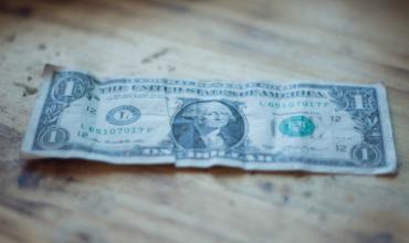 a one dollar bill on a wooden table