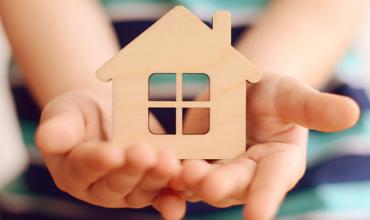 hands holding a wooden house