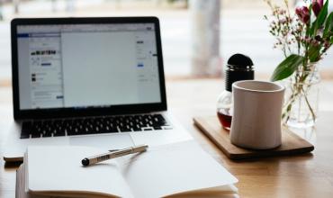 a table with a computer, journal and coffee