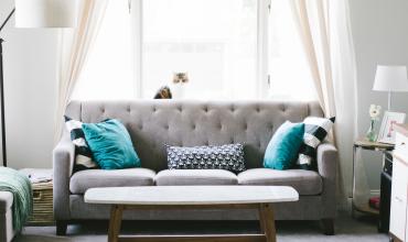 A gray couch with blue pillows and a coffee table in front of it