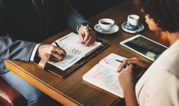 two people sitting at a desk doing finance work