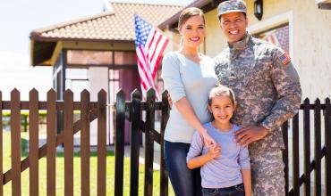 A military family standing in front of their home