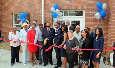 folks cutting a ribbon outside of an apartment complex in charlotte