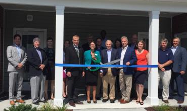 guests lining up to cut the ribbon on the porch of Wakefield Commons apartments