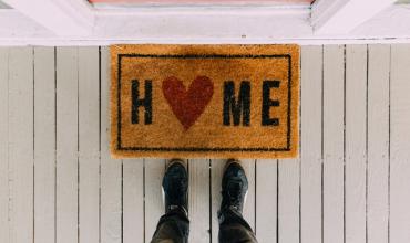 A front door mat that says "Home" with a heart for the "O"