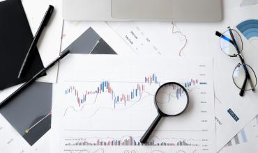 A magnifying glass sitting on a paper with graphs