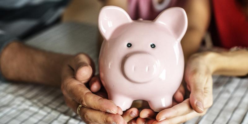 Two hands holding a piggy bank