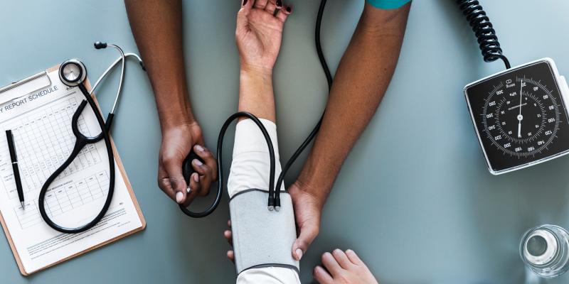 Picture of two people's arms, one is checking the other's blood pressure