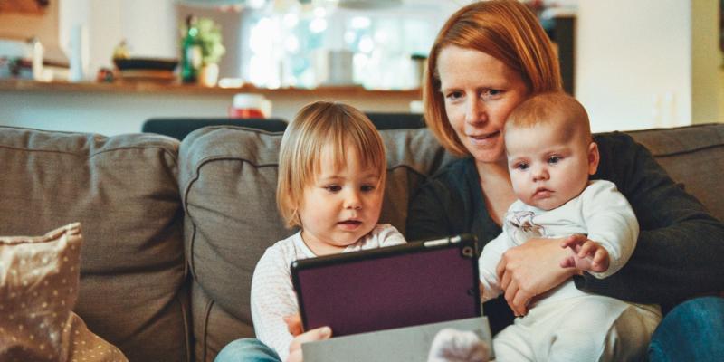 mom and two kids looking at a tablet