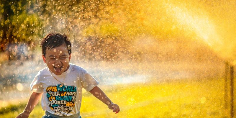 a kid running through a sprinkler