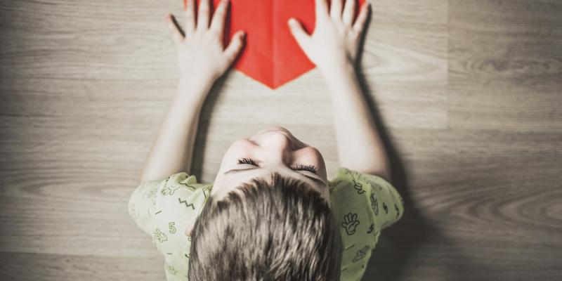 child with a red paper heart