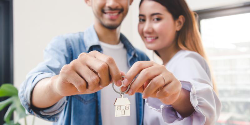 Two people holding up keys to their new home