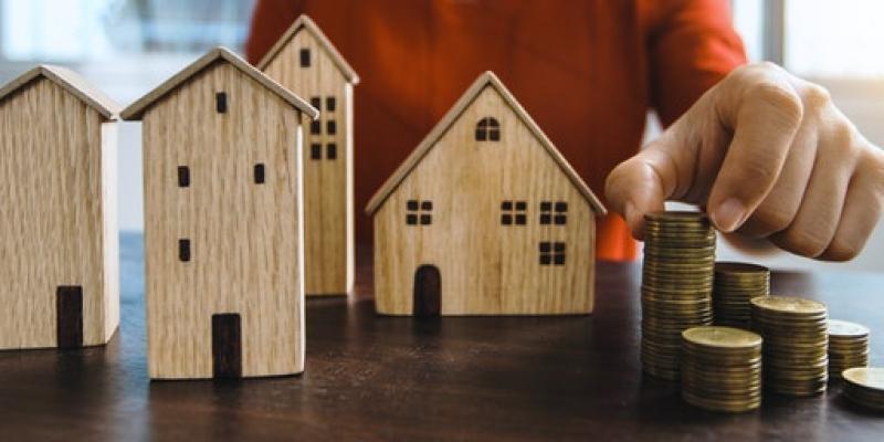 Array of small wooden houses on a table with coins