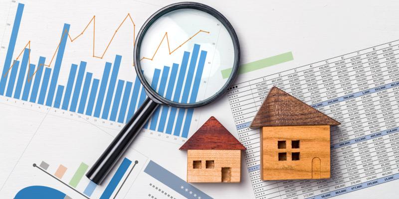 A magnifying glass and little houses over paper reports